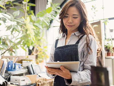 A woman in overalls is using a tablet in a store.