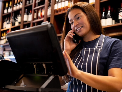 A bartender talking on the phone at a wine bar.