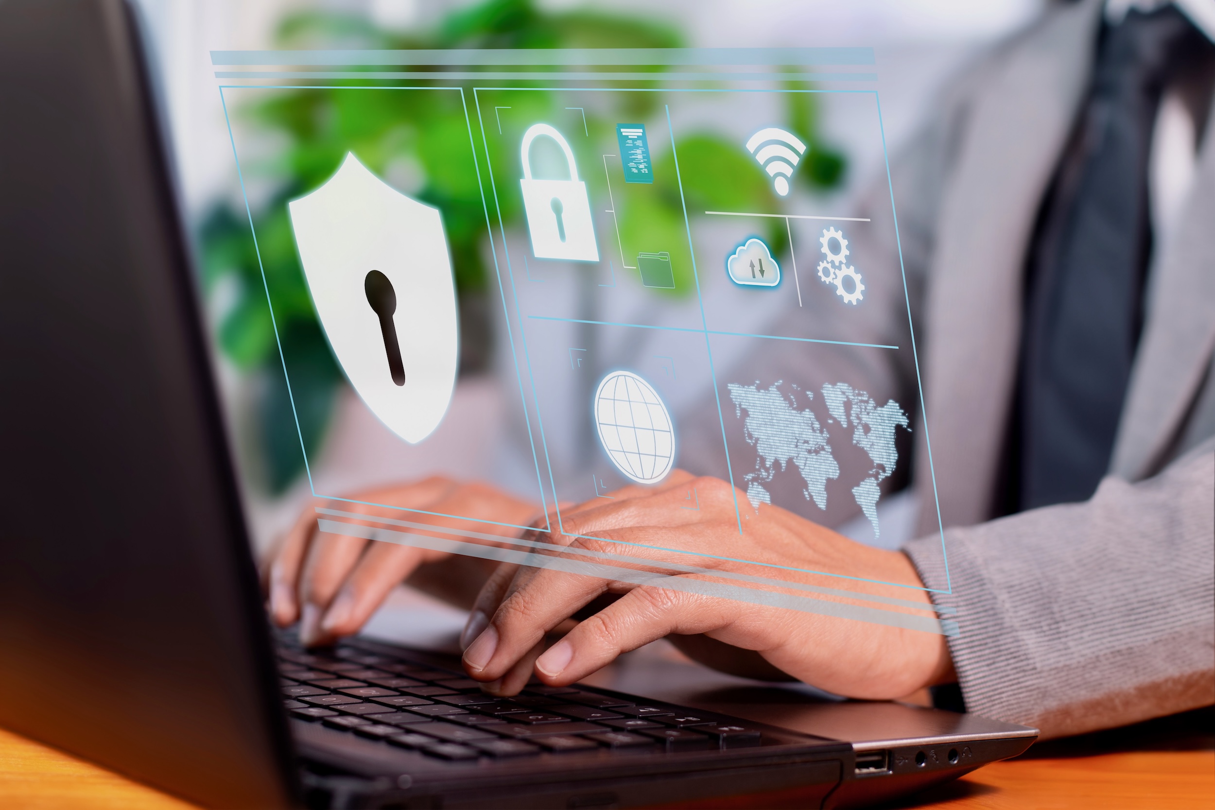 A person in business attire types on a laptop with virtual cybersecurity icons, such as a lock, shield, and global network, displayed in the foreground.