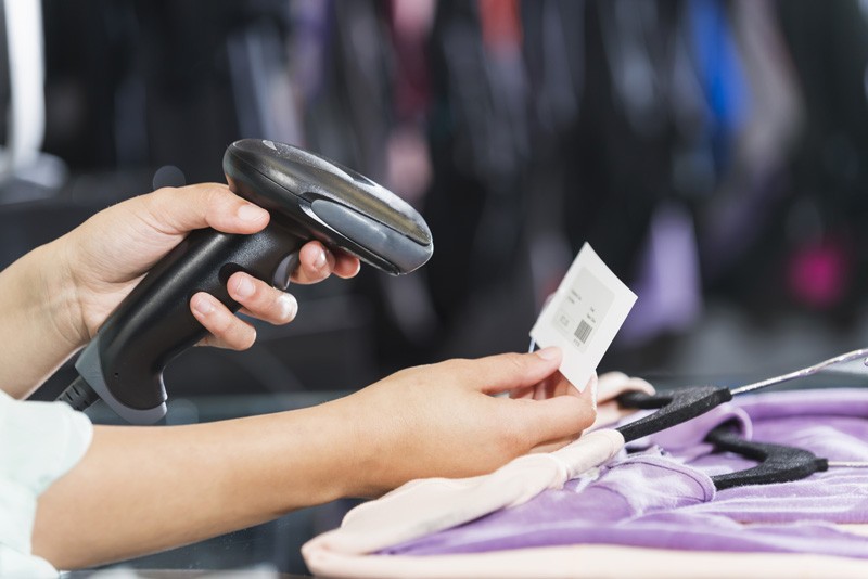 A woman is using a scanner in a clothing store.