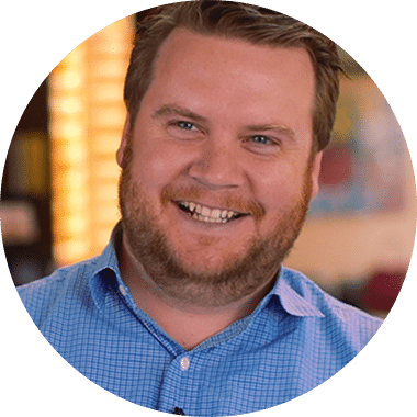 A man with a beard smiling in a blue shirt.